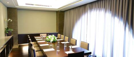 A conference room with a long table, chairs, and a potted plant.