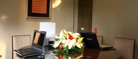 Uma mesa de conferência com dois laptops, um rato e um vaso de flores.