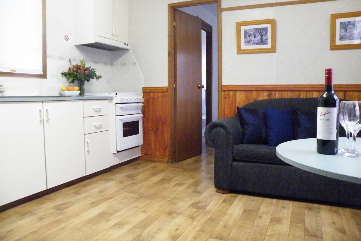 Eine Küche mit weißen Schränken, einem Herd und einem Essbereich mit einer Couch und einem Tisch.