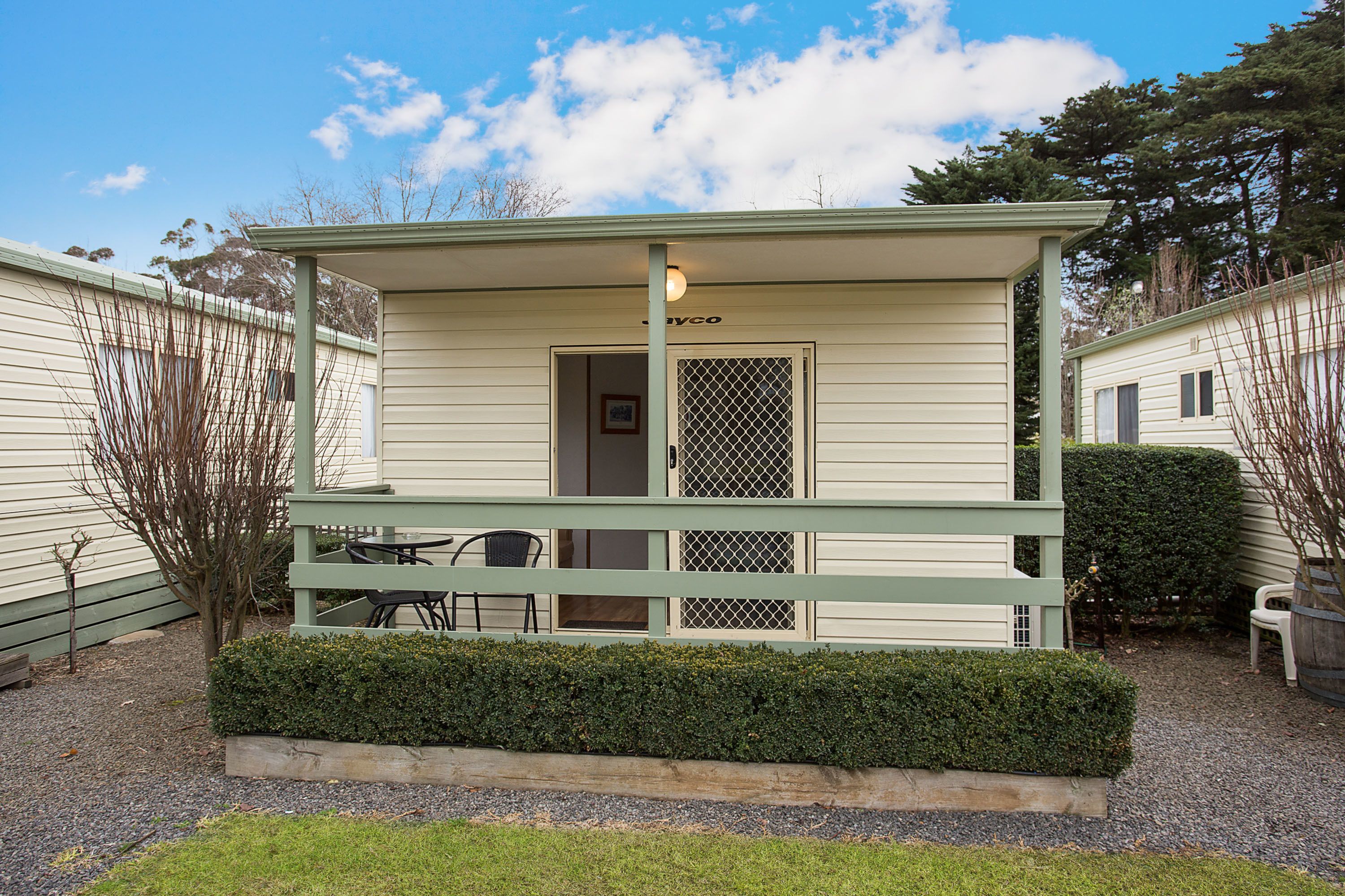 A small, single-story building with a porch, a door, and a window with a mesh screen.
