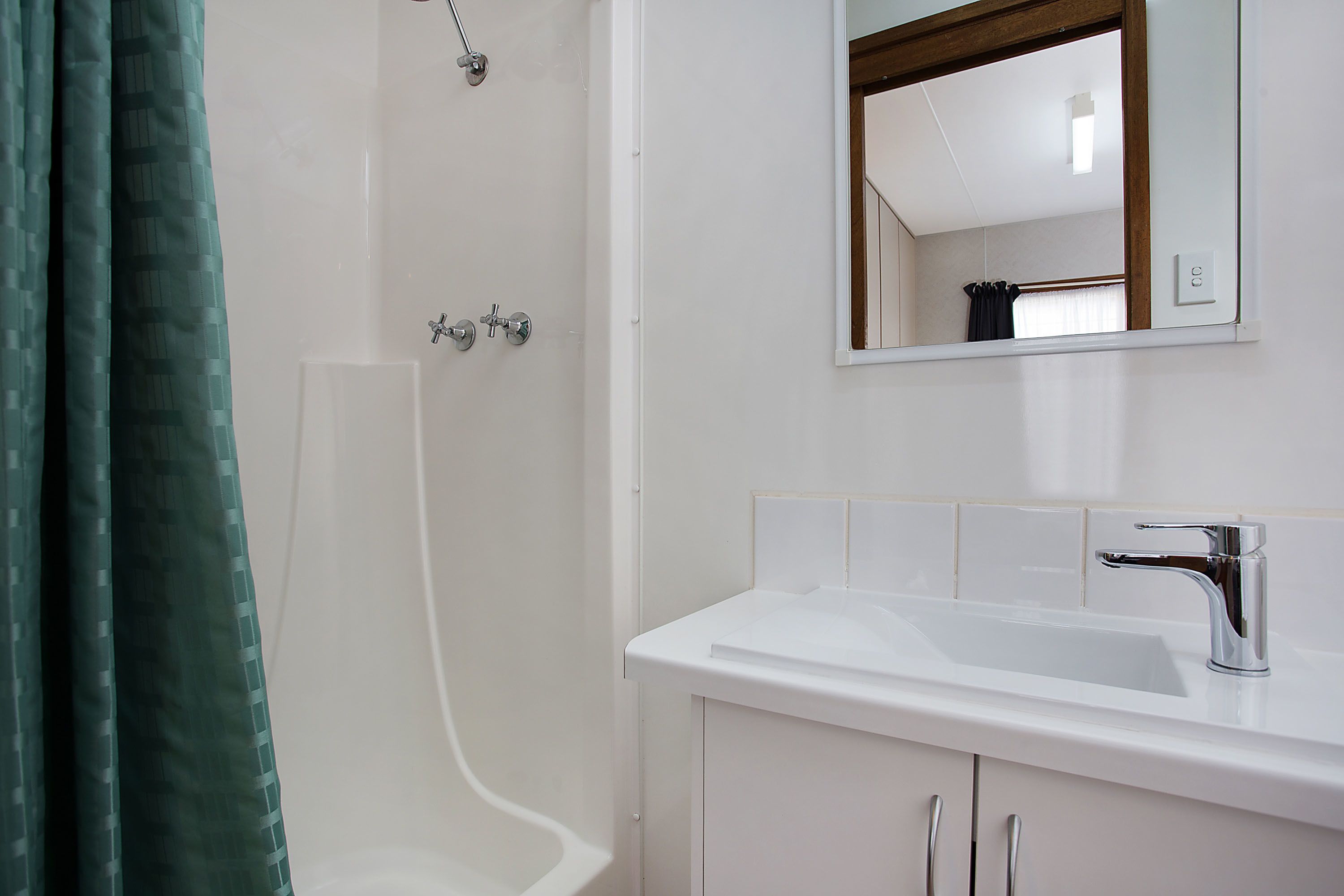 A bathroom with a shower, a sink, and a mirror.