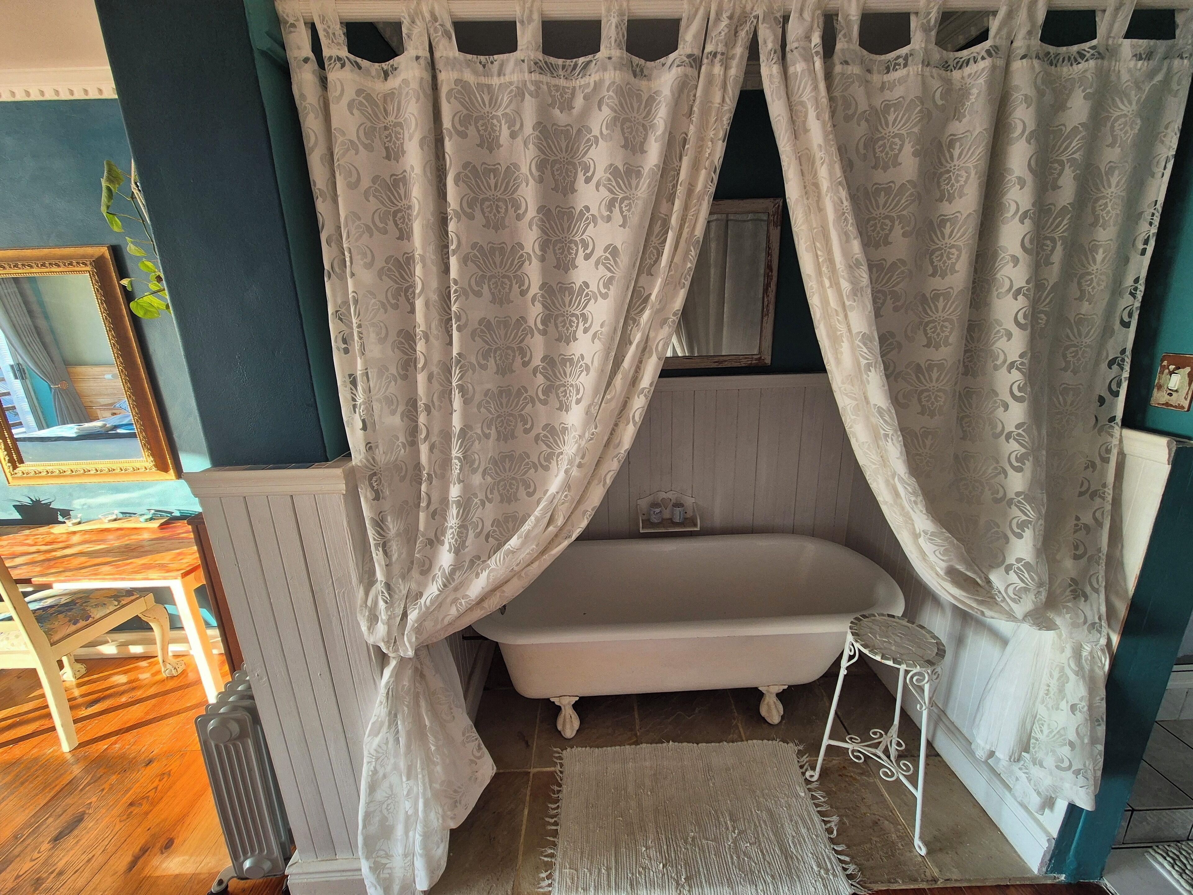 Casa de banho com banheira, espelho e um banquinho pequeno.