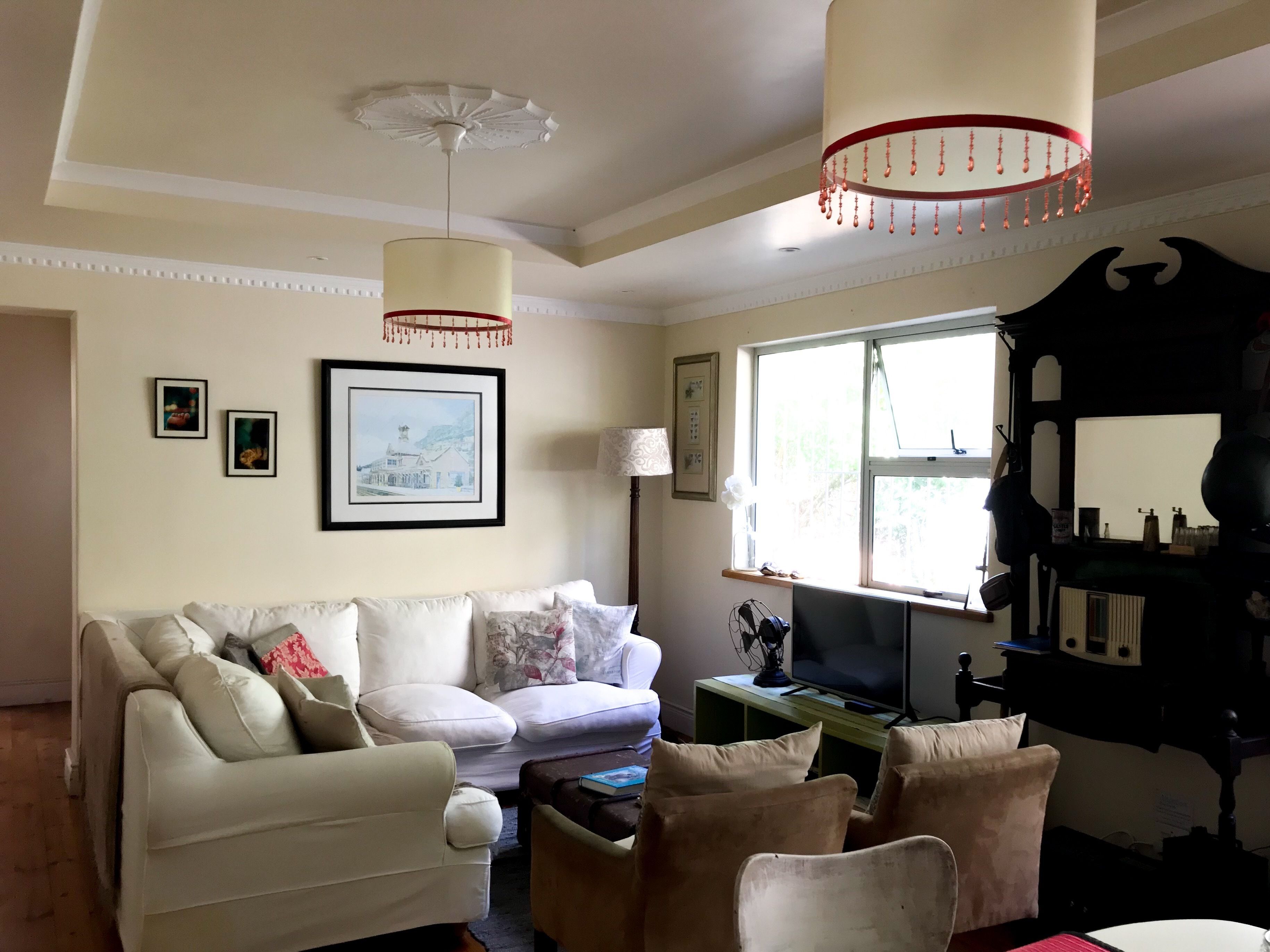 Een woonkamer met een witte bank, een televisie en een groot raam.