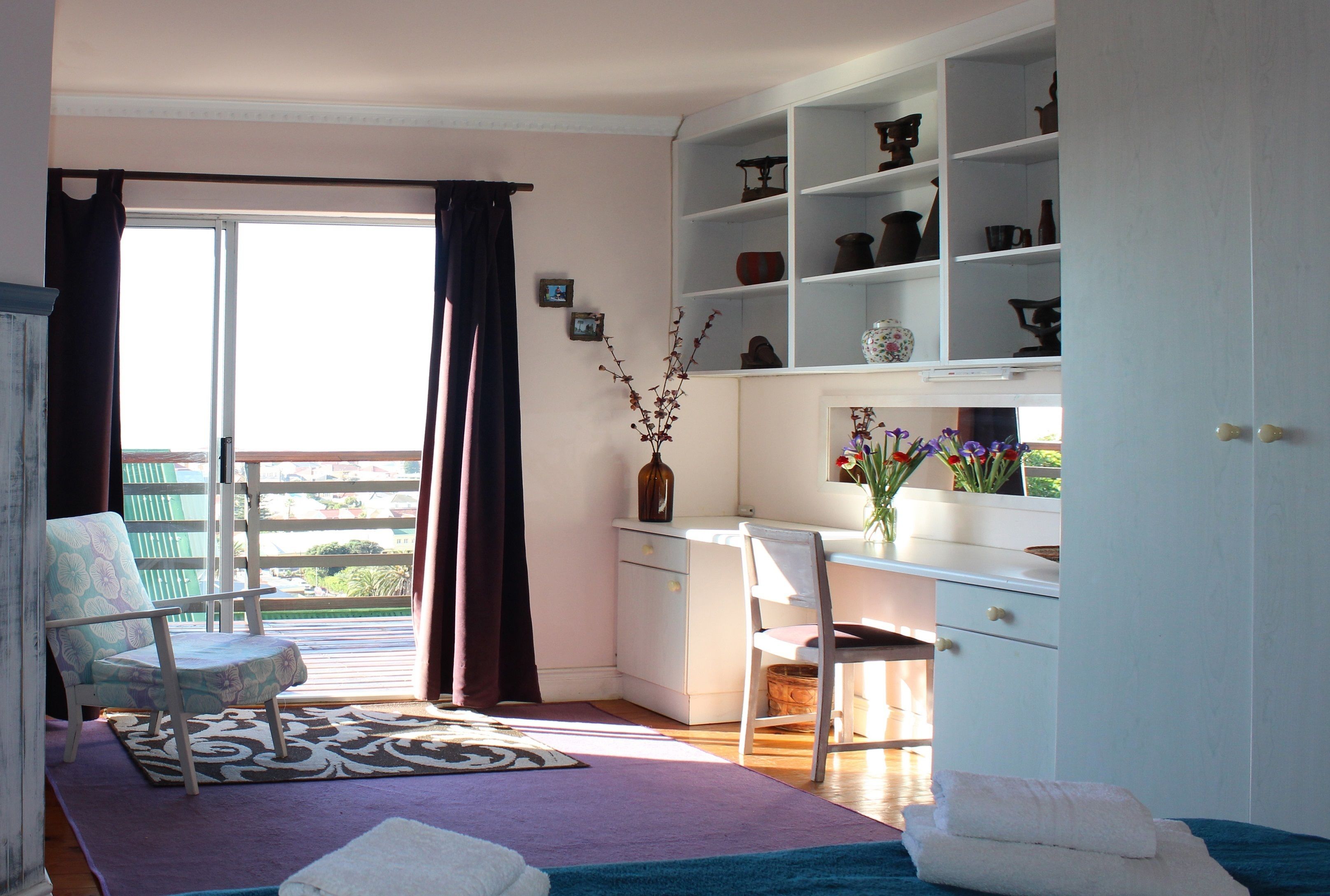 Een kamer met een bureau, stoel en wandplanken met decoratieve objecten.