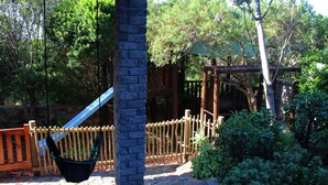 A wooden swing set, a stone pathway, and a wooden fence in a park setting. - Bluebottle Guest House (Cape Town)