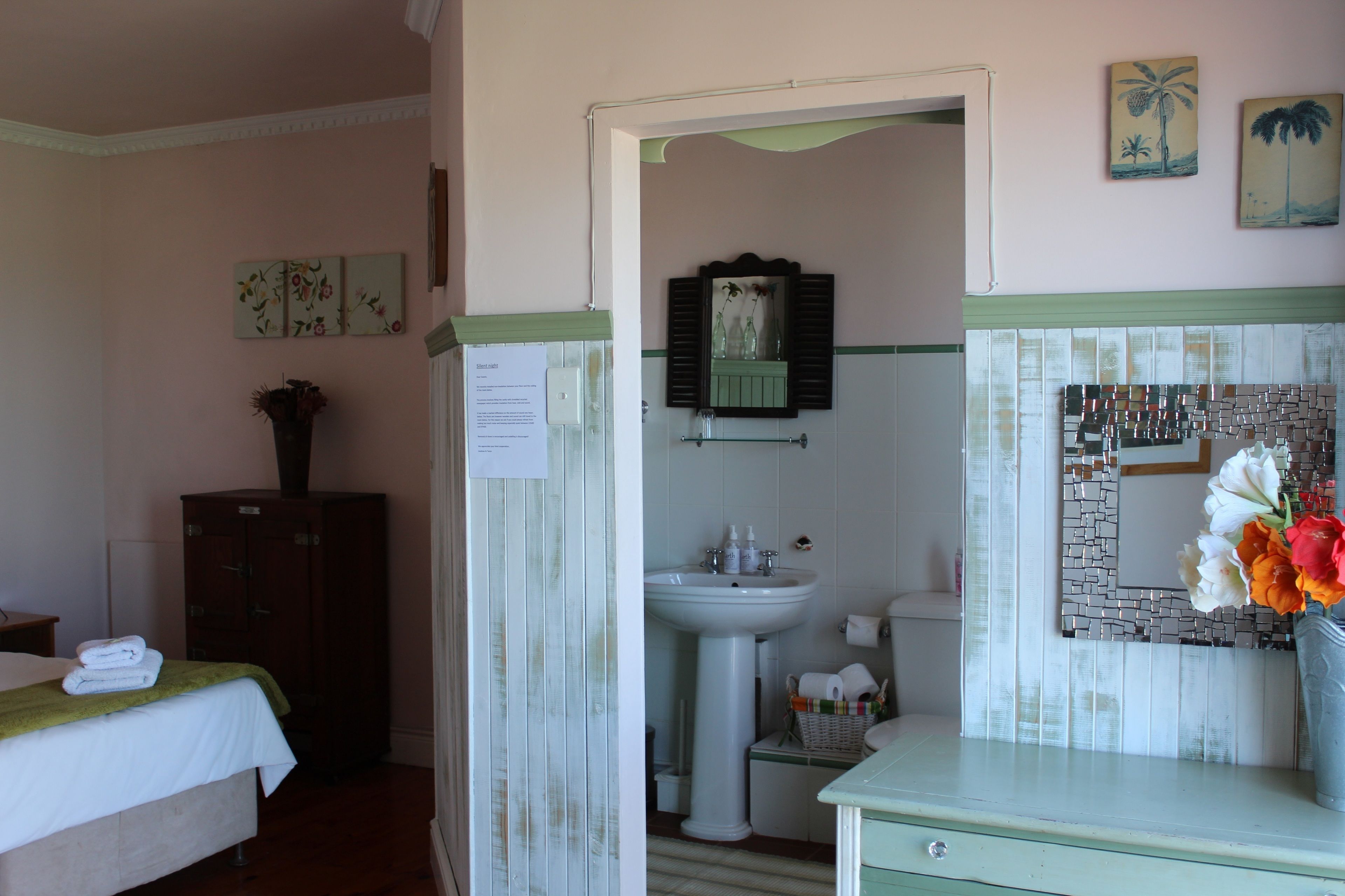 A hotel room with a bed, a dresser, a vanity with a mirror, and a sink.