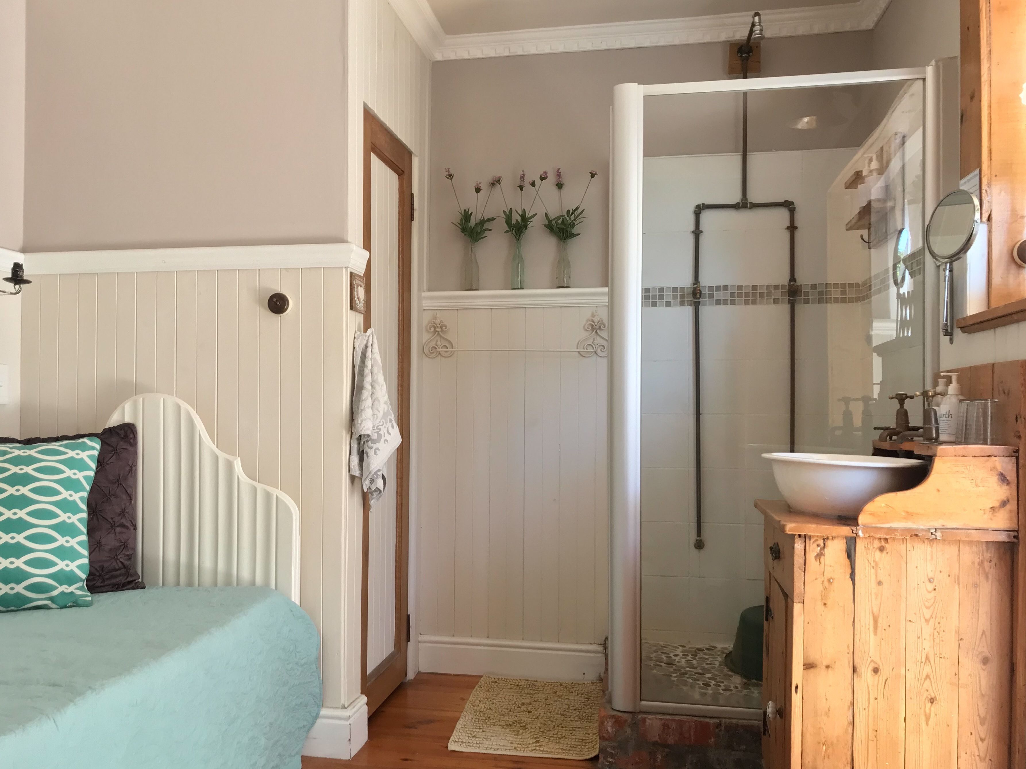 A bedroom with a bed, a wooden cabinet, and a bathroom with a shower and toilet.