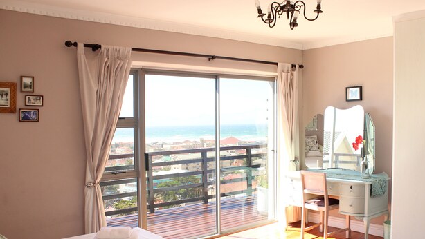 A bedroom with a large sliding glass door leading to a balcony with a city view. - Bluebottle Guest House (Cape Town)
