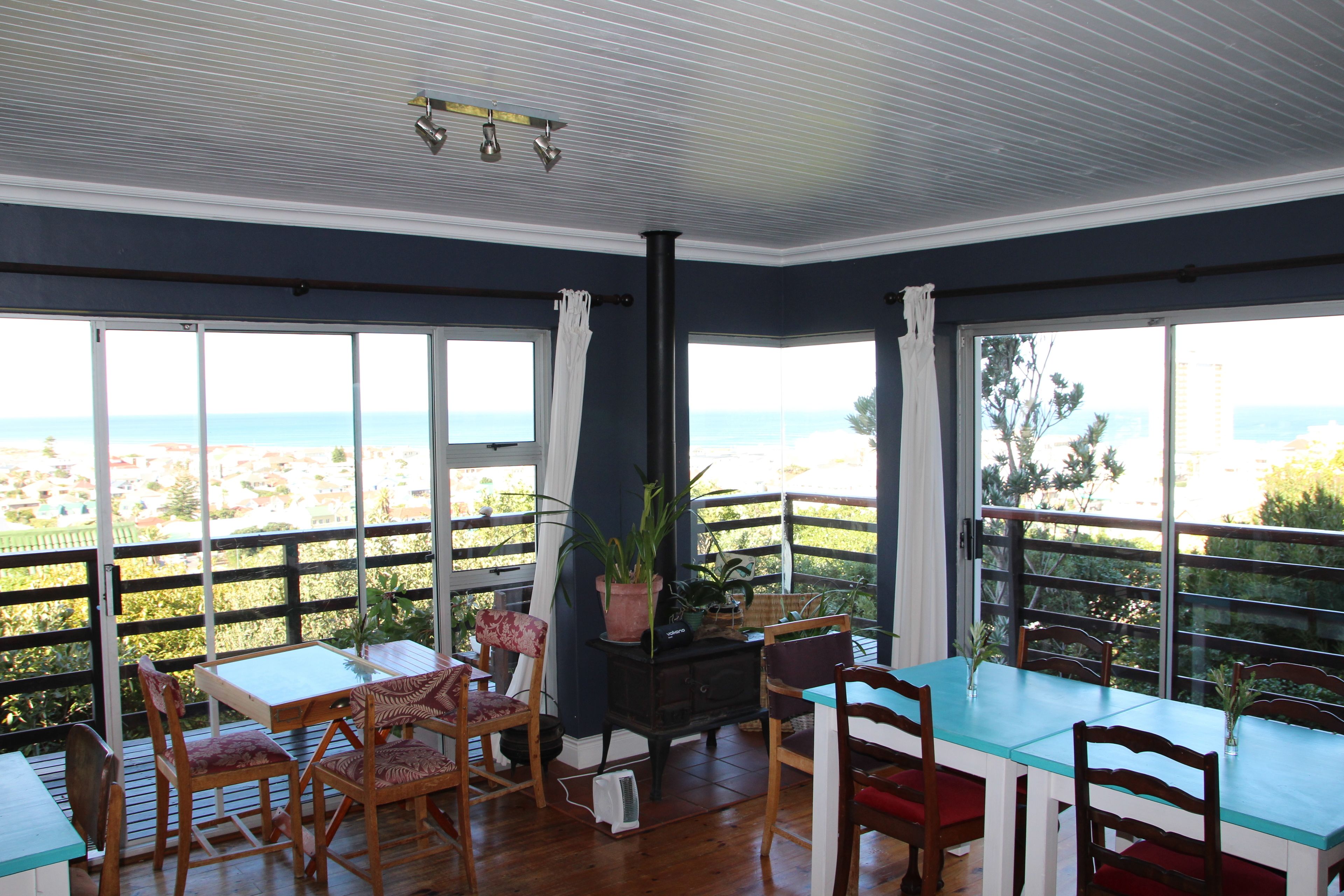 A dining area with a view of the ocean, featuring a table, chairs, and a potted plant.