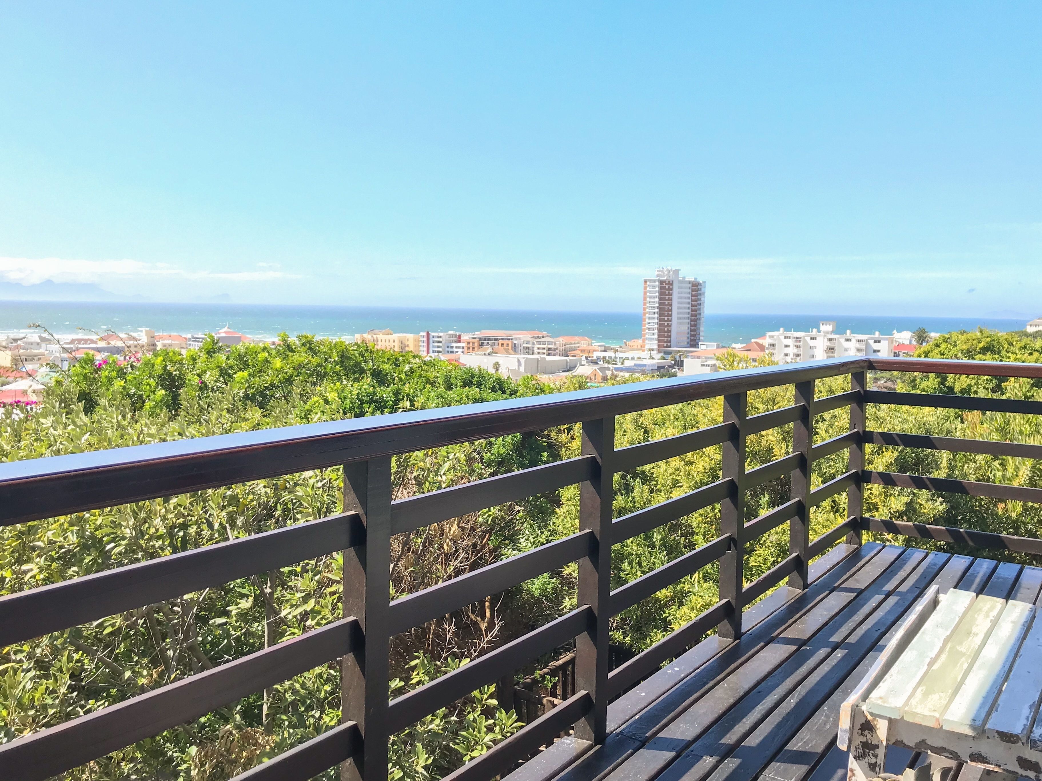 A balcony with a view of a coastal cityscape, including buildings and the sea.