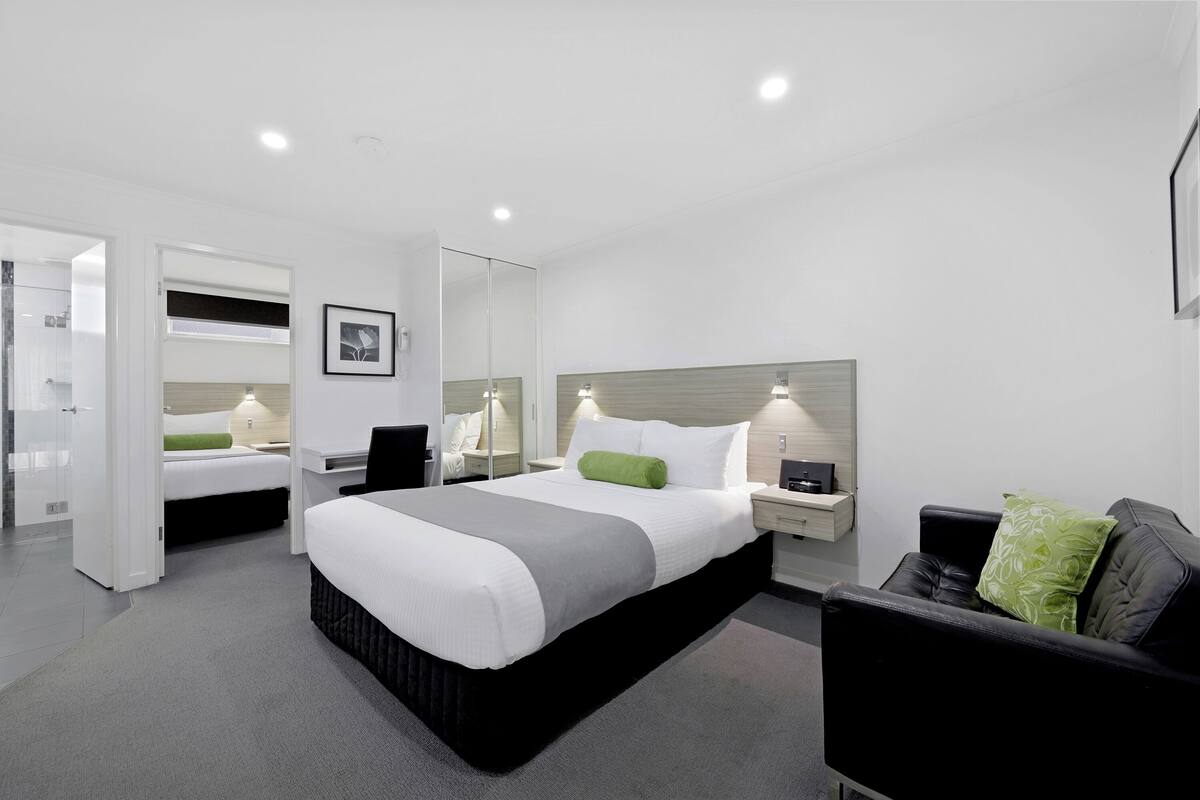 Une chambre d’hôtel moderne dotée d’un grand lit, d’un coin salon séparé et d’un dressing.