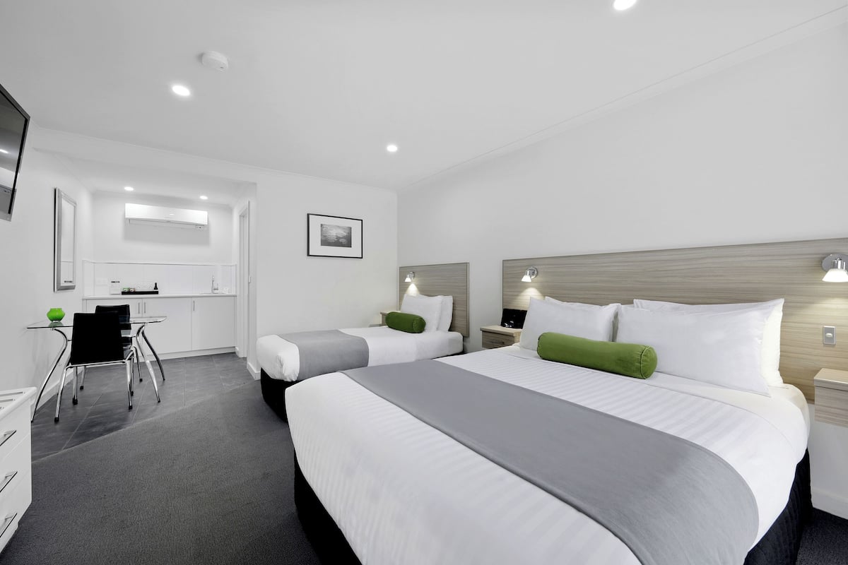 Une chambre d’hôtel avec deux lits, un bureau et une chaise.