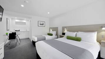 A hotel room with two beds, a desk, and a chair.