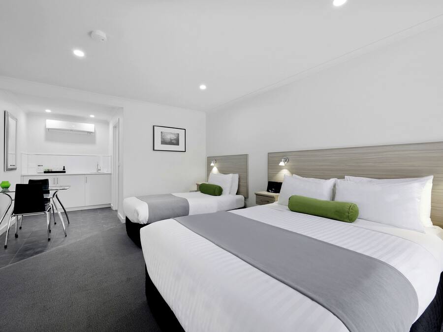 Une chambre d’hôtel avec deux lits, un bureau et une chaise.