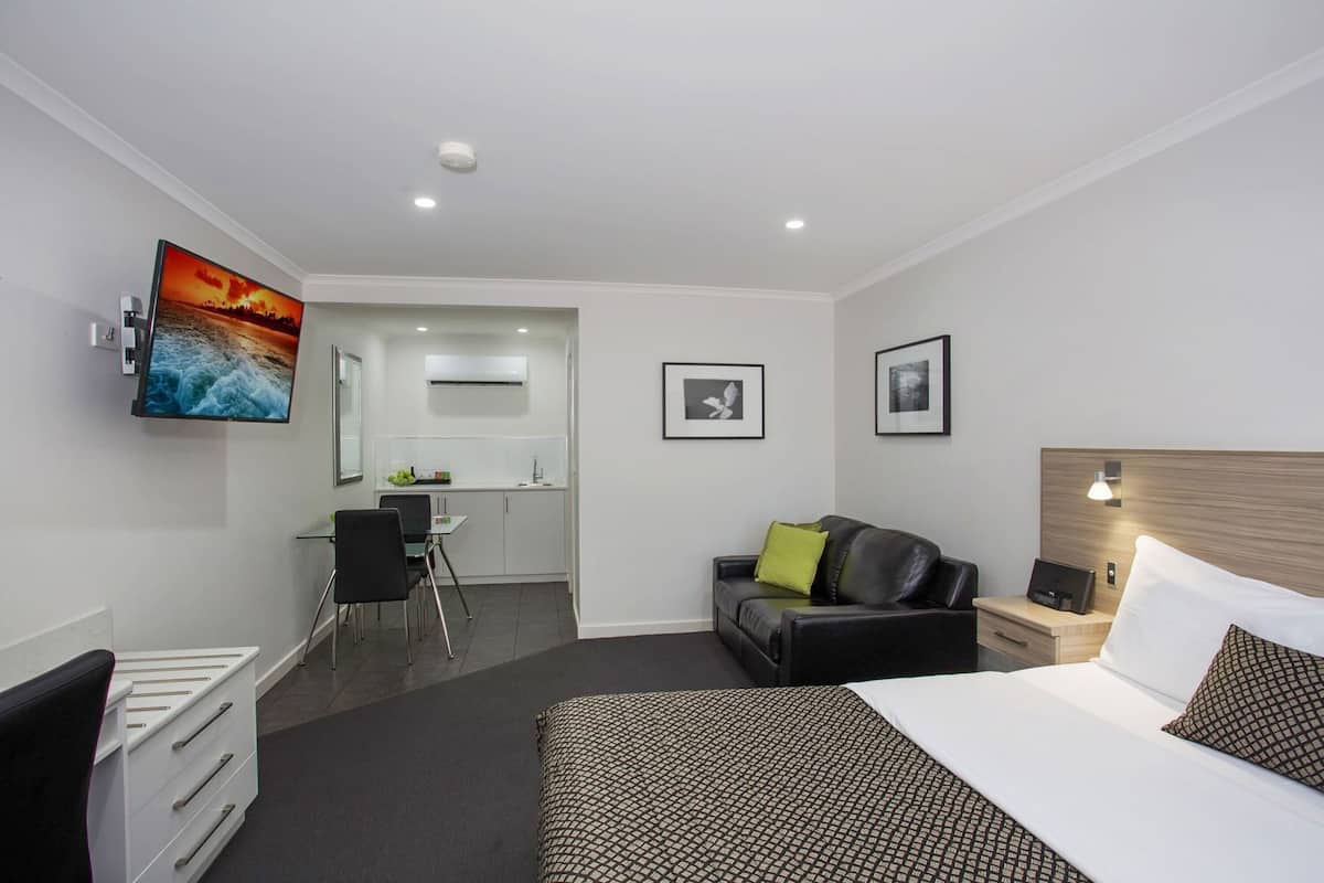 Une chambre d’hôtel avec un lit, un bureau, une chaise, un canapé et un téléviseur.