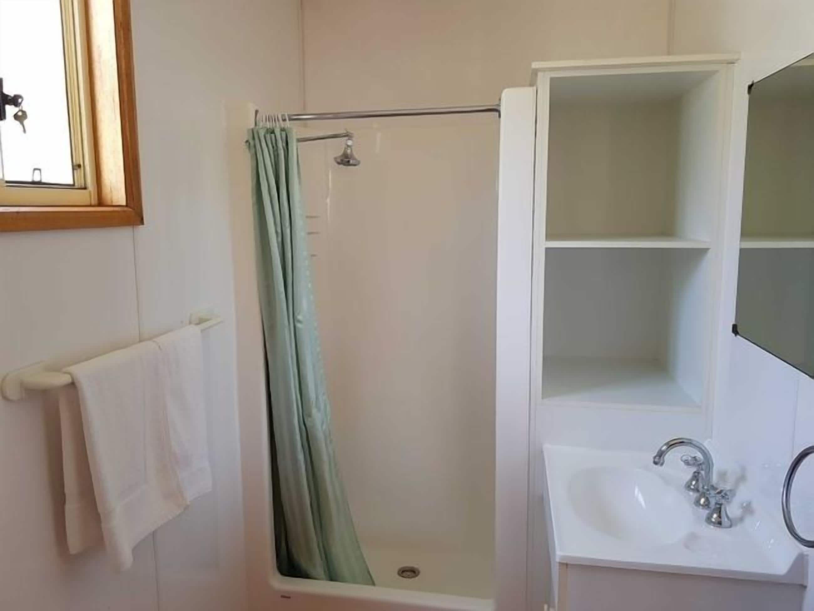 Un bagno con doccia, lavabo e specchio.