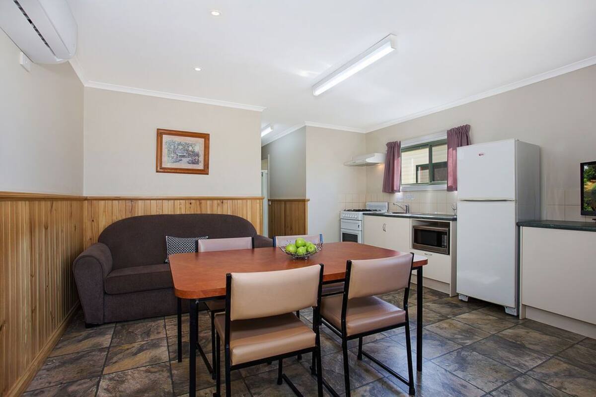Una cocina compacta con mesa y sillas, refrigerador y estufa.