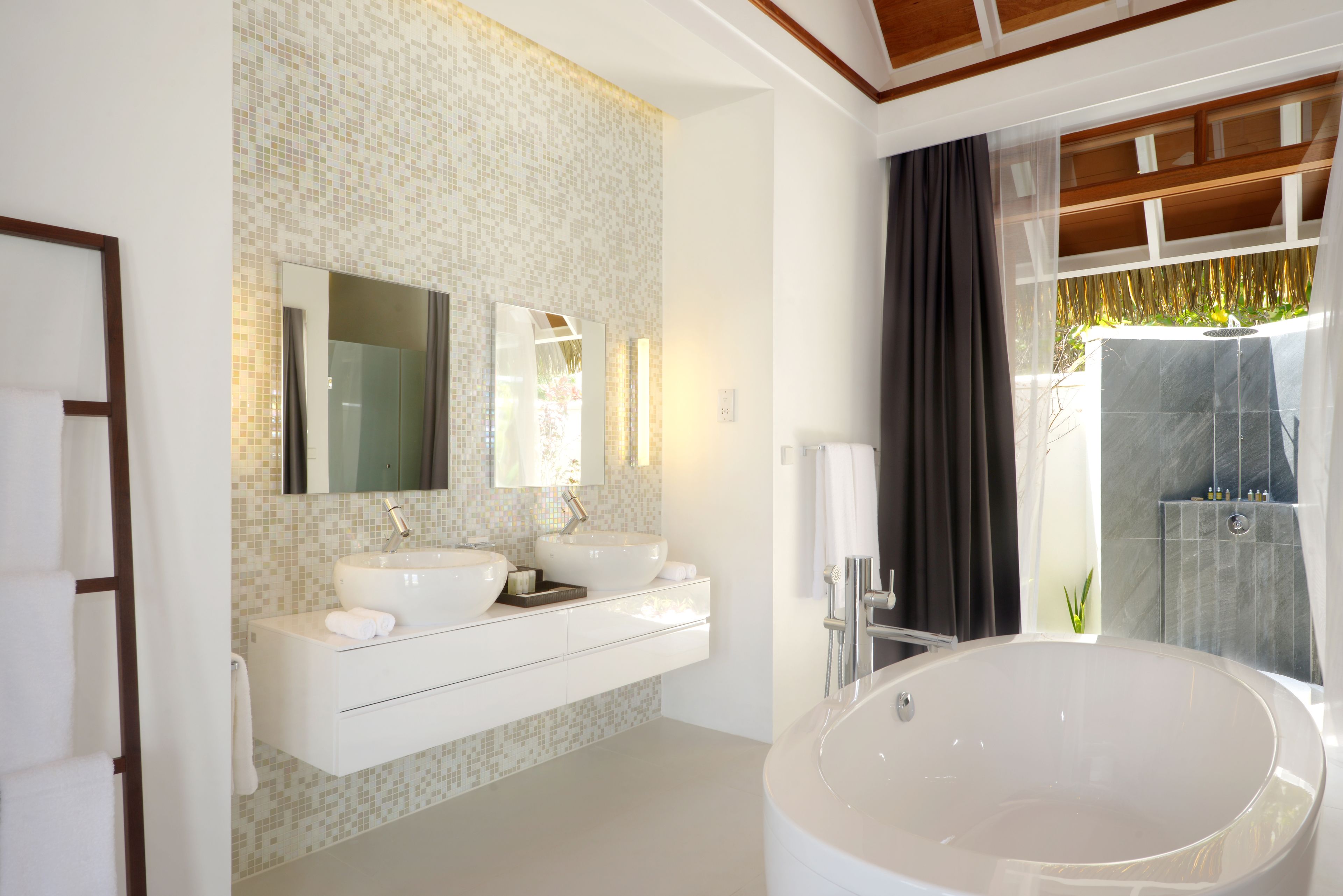 A modern bathroom with two sinks, a large bathtub, and a shower area.