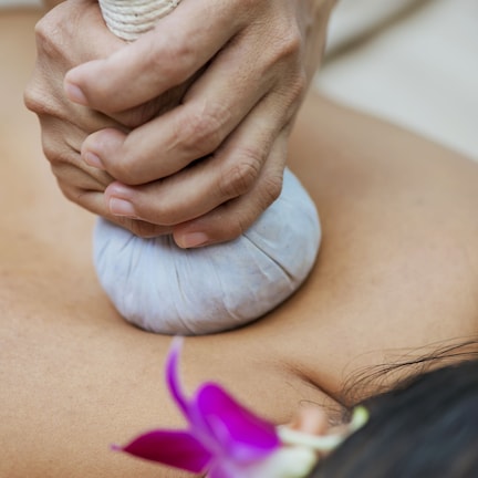 A close-up of hands applying a massage tool to a person's back.