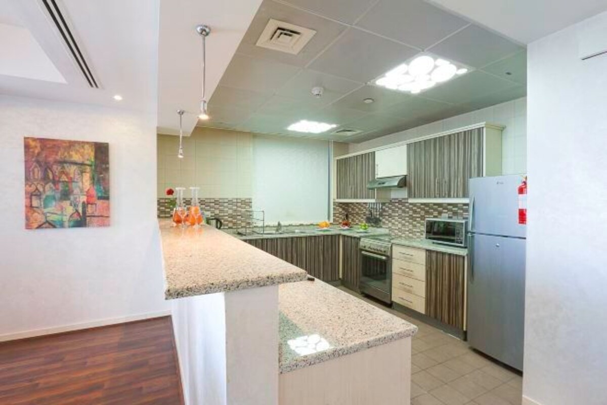 Cocina moderna con encimeras de granito, electrodomésticos de acero inoxidable y salpicadero de azulejos.