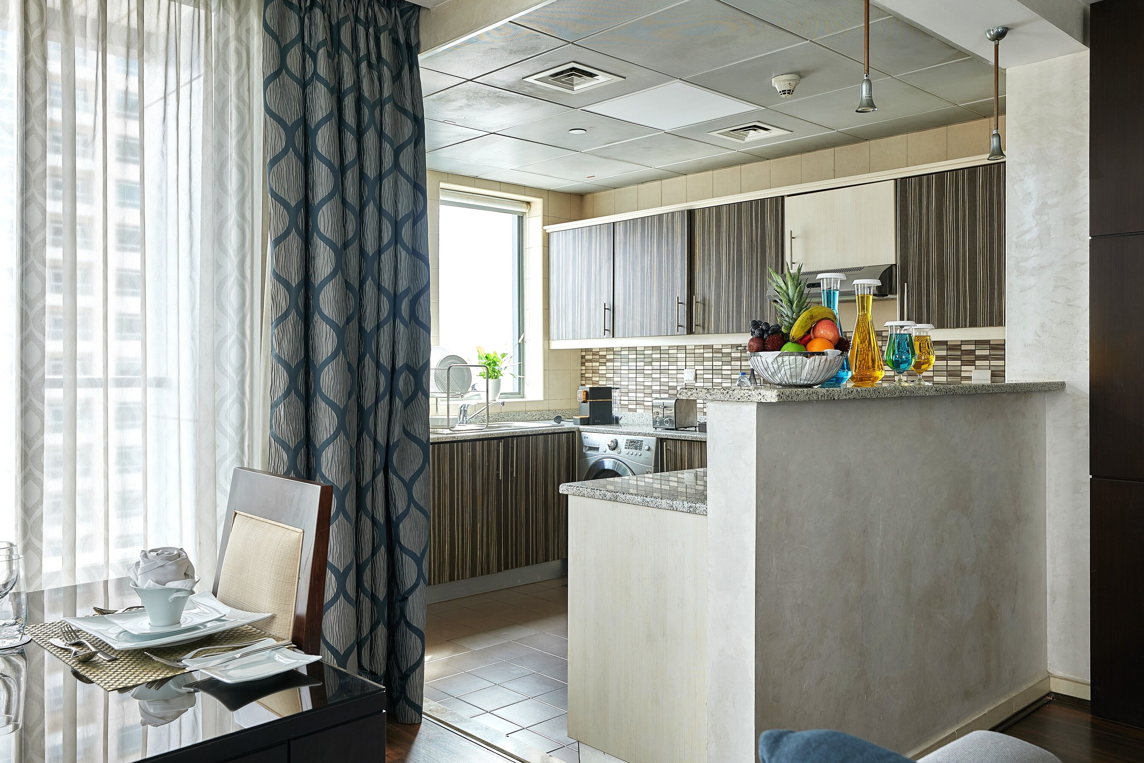 A modern kitchen with a central island, built-in appliances, and a dining area with a glass table and chairs.