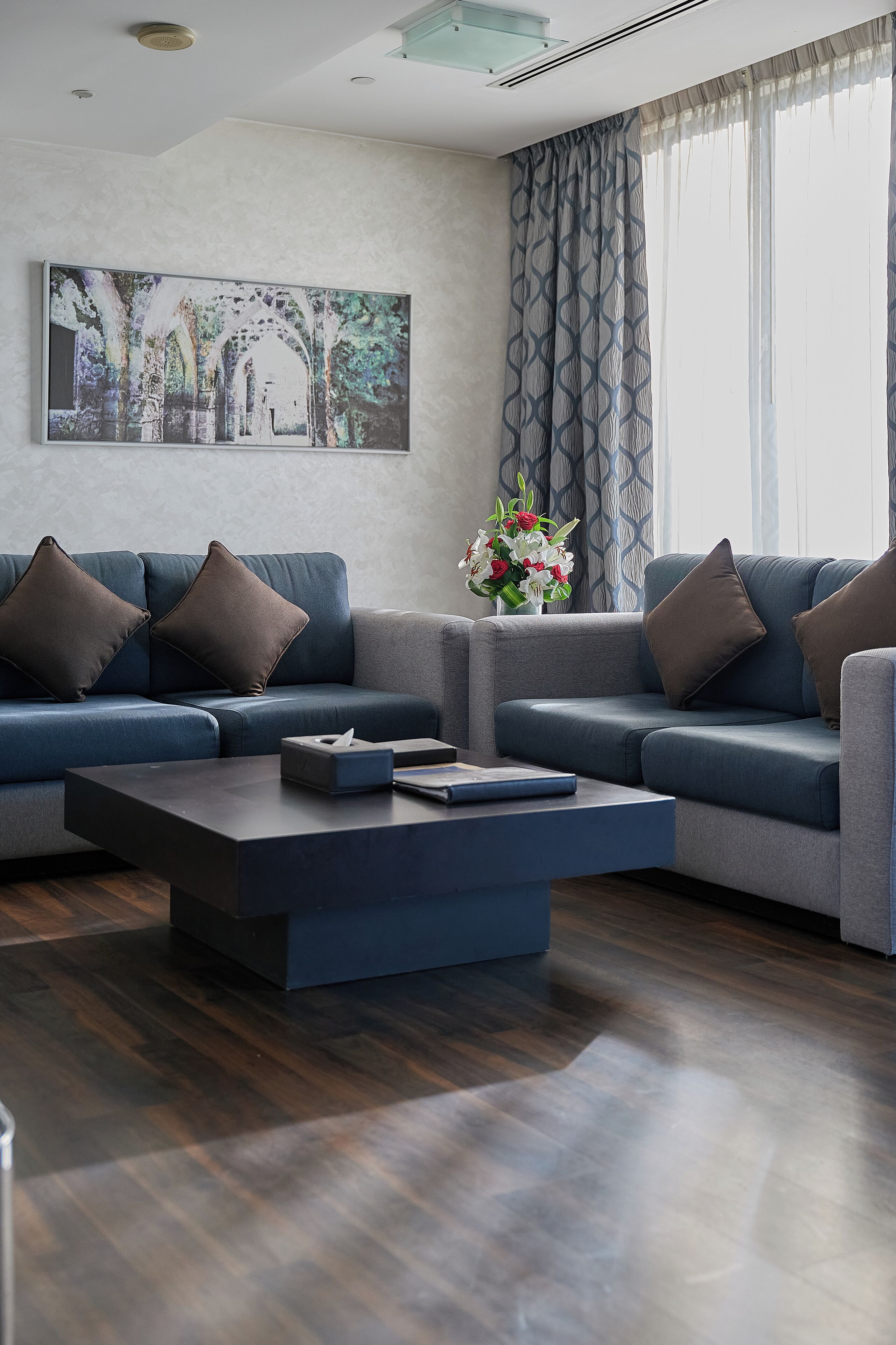 A modern living room with a sectional sofa, a coffee table, and a large framed picture on the wall.