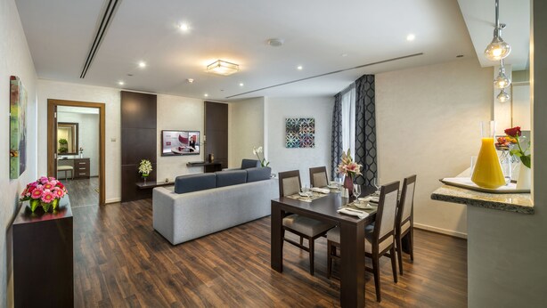 Una sala de estar moderna con comedor, piso de madera y un sofá gris.