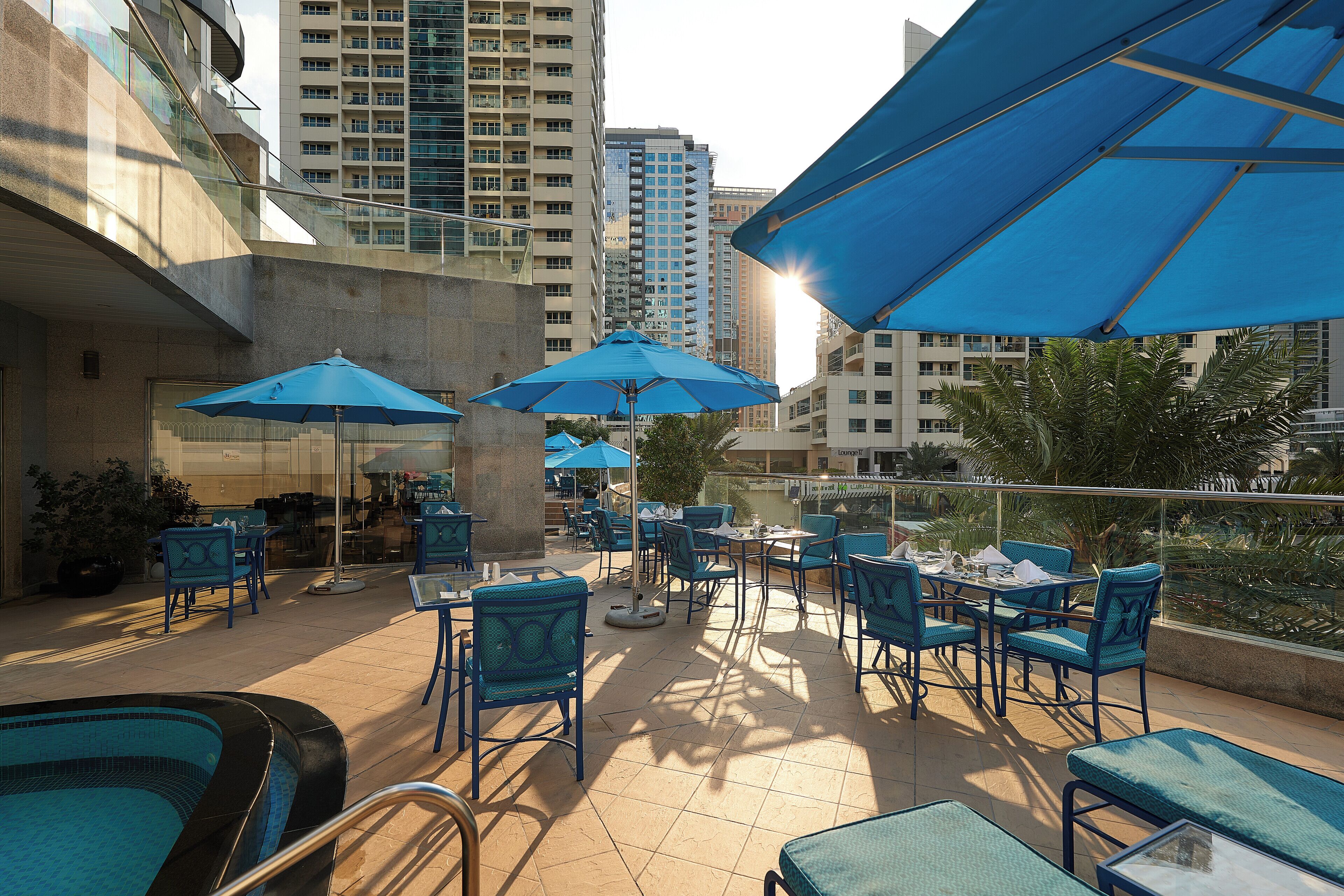 An outdoor patio with blue umbrellas, lounge chairs, and a pool area.