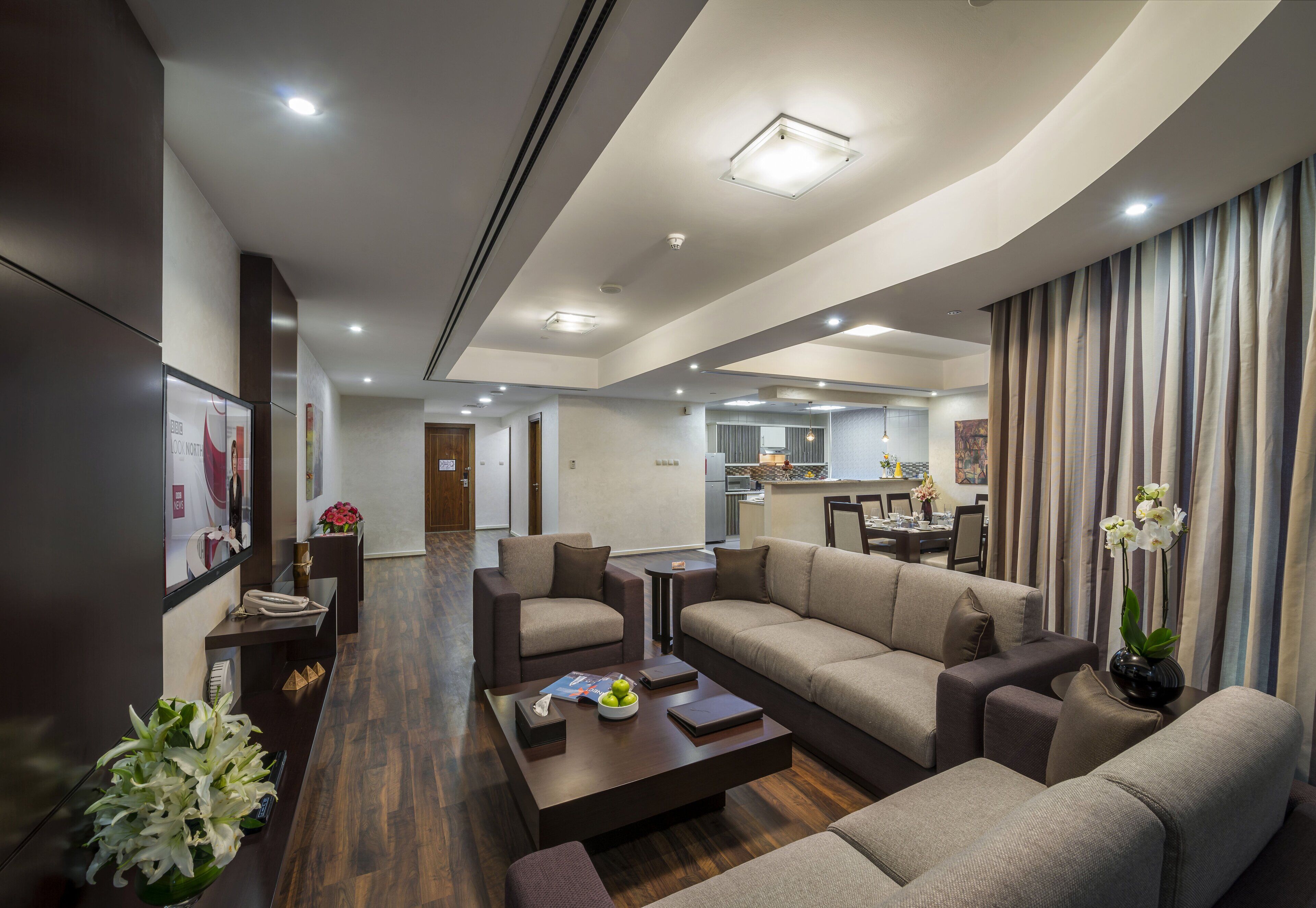A modern living room with a sofa set, coffee table, and a dining area in the background.