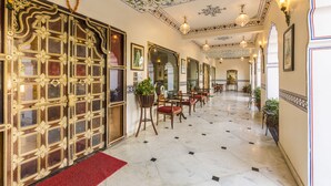A hallway with ornate doors, chandeliers, and patterned ceiling. - Umaid Residency - A Regal Heritage Home (Amer)