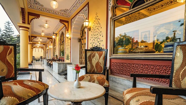 A hotel lobby with ornate decor, a marble floor, and a view of the outdoors through a large window. - Umaid Residency - A Regal Heritage Home (Amer)
