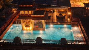 En pool på taket med en central fontän, omgiven av ett takförsett sittområde med stolar och bord.