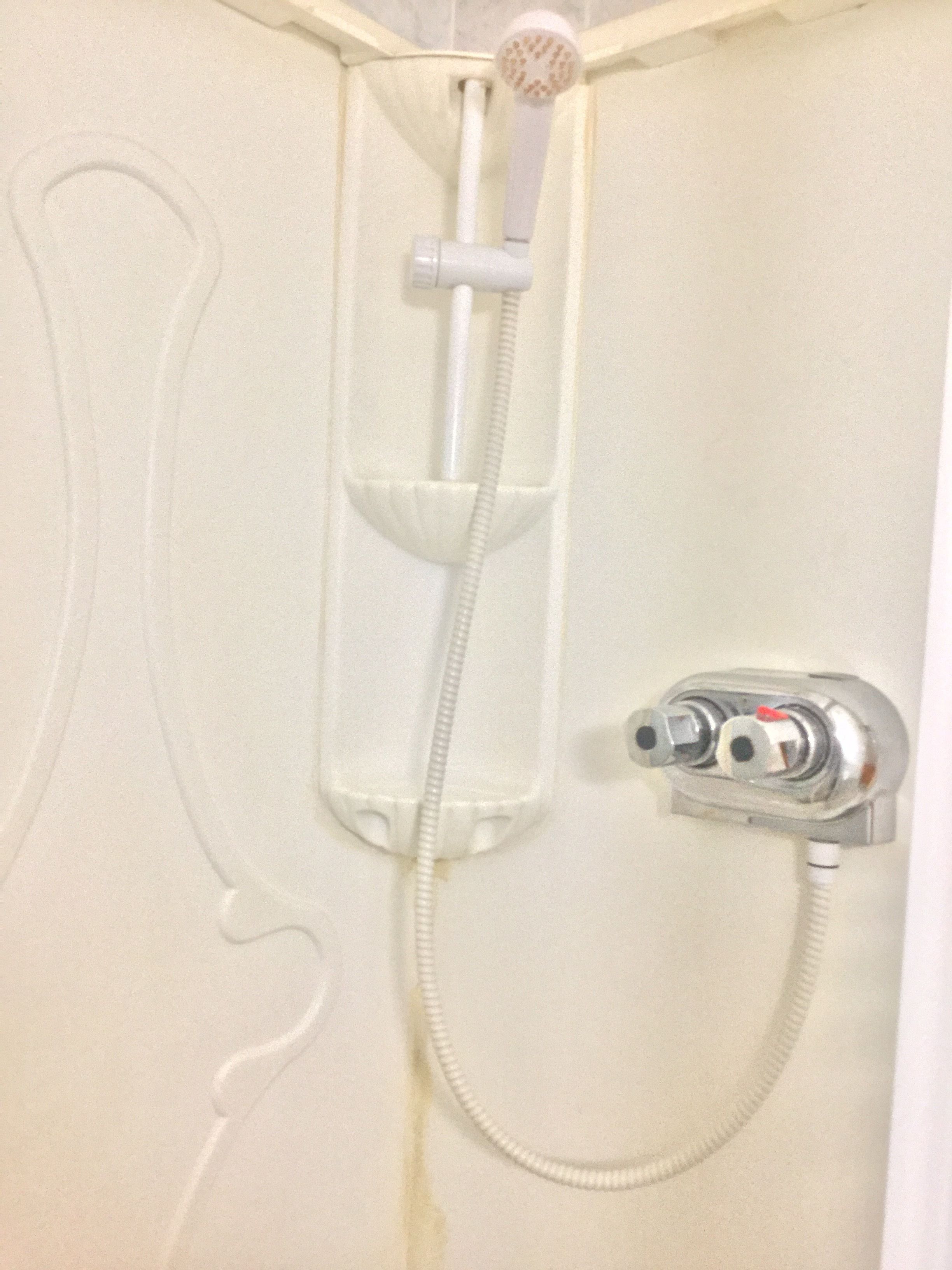 A shower with a handheld showerhead and a wall-mounted control valve.