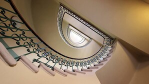 Una escalera de caracol con barandilla de metal decorativa y un tragaluz en la parte superior.