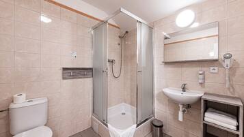 A modern bathroom with a glass-enclosed shower, a sink, and a toilet.