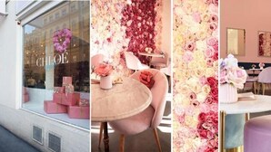 Interior de un hotel boutique con una pared floral, una recepción y un área de estar.