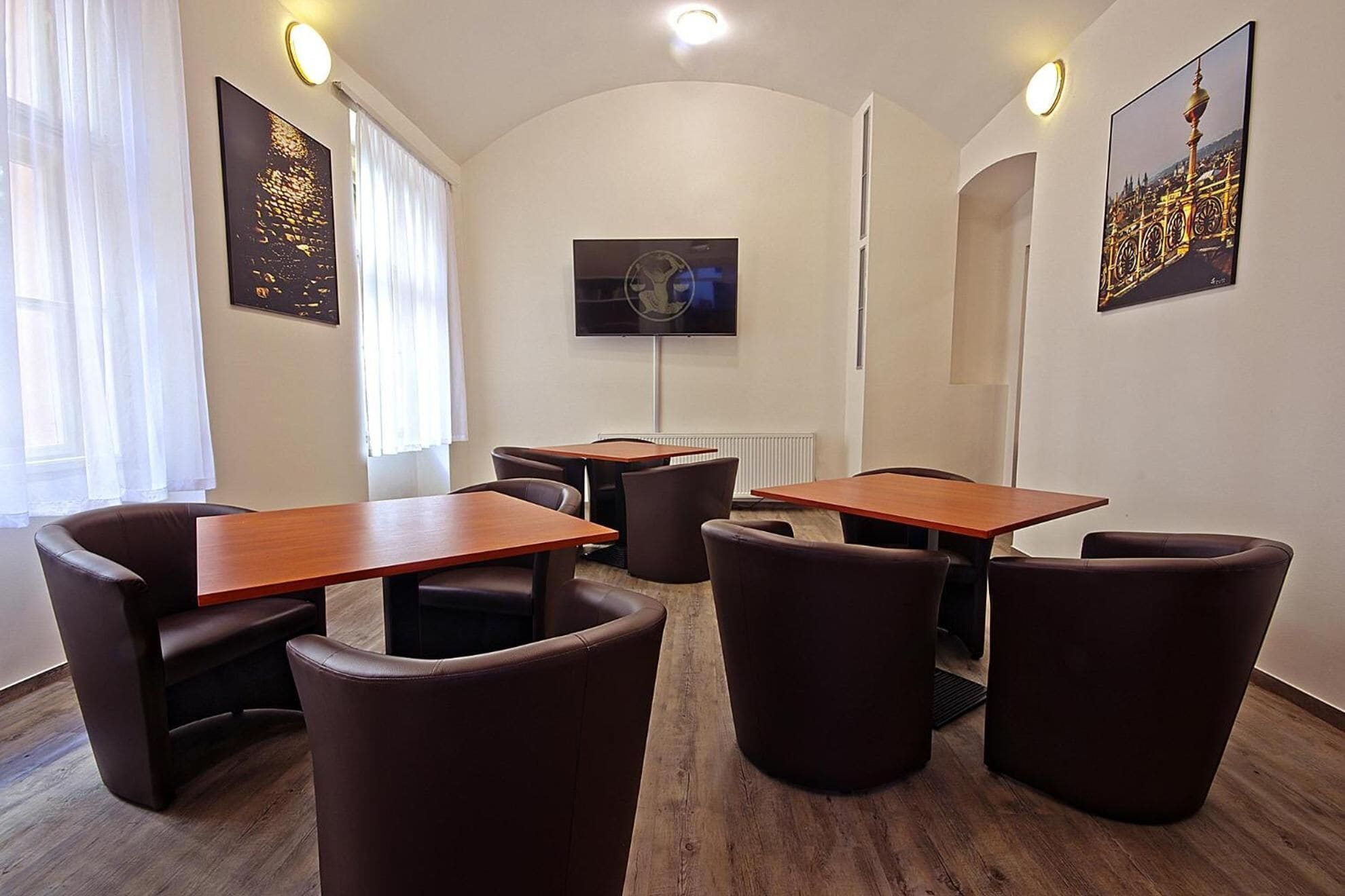 Uma sala de conferências moderna com mesas de madeira, cadeiras de couro, uma TV de tela plana e obras de arte nas paredes.