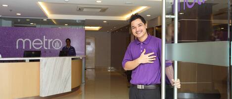 A hotel reception area with a Metro sign, a reception desk, and a modern interior design.