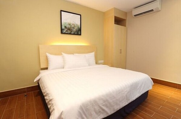 Una habitación de hotel con una cama grande, un cabecero, un aire acondicionado de pared y un cuadro enmarcado.