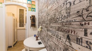 A bathroom with a white sink, a mirror, and a wall covered with vintage-style wallpaper. - Casale D'Or (Palermo)