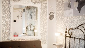 A bedroom with a bed, a mirror, a wall clock, and a decorative wall with a heart-shaped cutout. - Casale D'Or (Palermo)