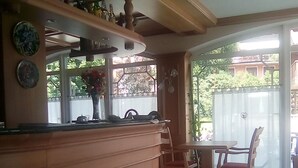 A kitchen with a wooden countertop, a dining table with chairs, and a view of the outside through a window. - Garní al Nardis (Carisolo)