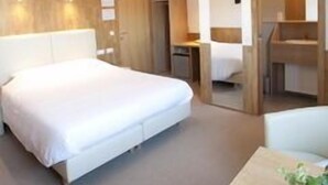 A modern hotel room with a large bed, a desk, and a walk-in closet. - Hotel Chamdor (Roeselare)