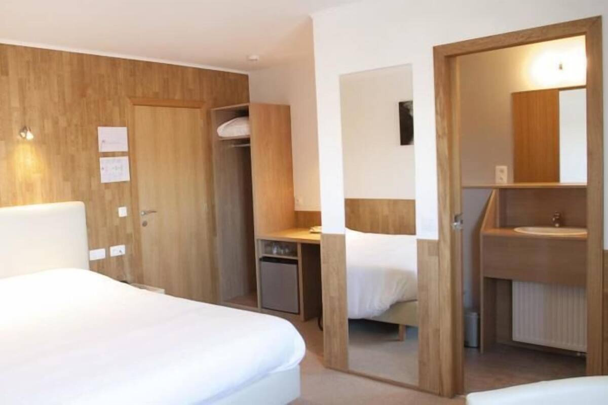 A hotel room with a large bed, a desk, a wardrobe, and a bathroom.