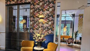 Een modern interieur met twee gele fauteuils, een bloemenwand en uitzicht op het omliggende landschap.
