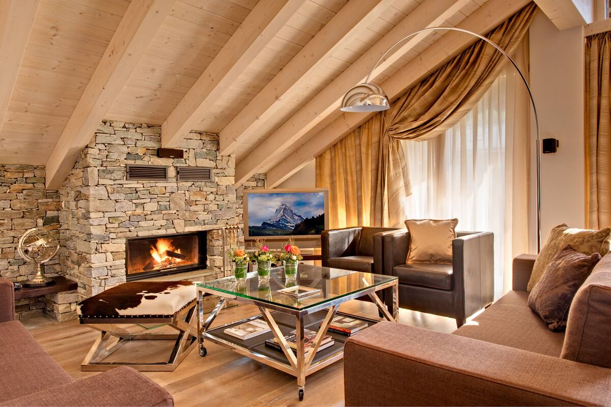 A cozy living room with a stone fireplace, leather sofa, and a glass coffee table.