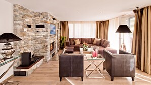 Un salon moderne avec une cheminée en pierre, des canapés en cuir et une table basse en verre.
