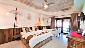 A hotel room with a large bed, two smaller beds, a desk, and a view of the outdoors.