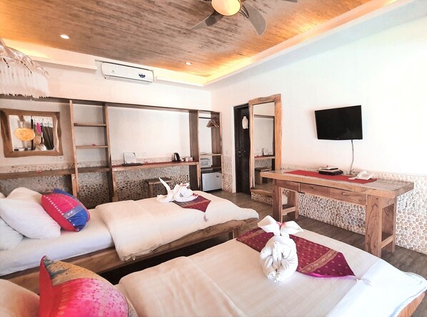 A hotel room with two beds, a desk, a television, and a mirror.