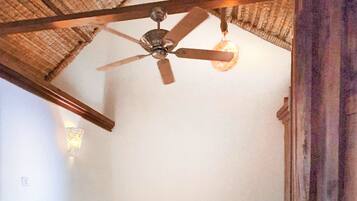 A bedroom with a bed, a bedside table, a ceiling fan, and a wall-mounted light fixture.